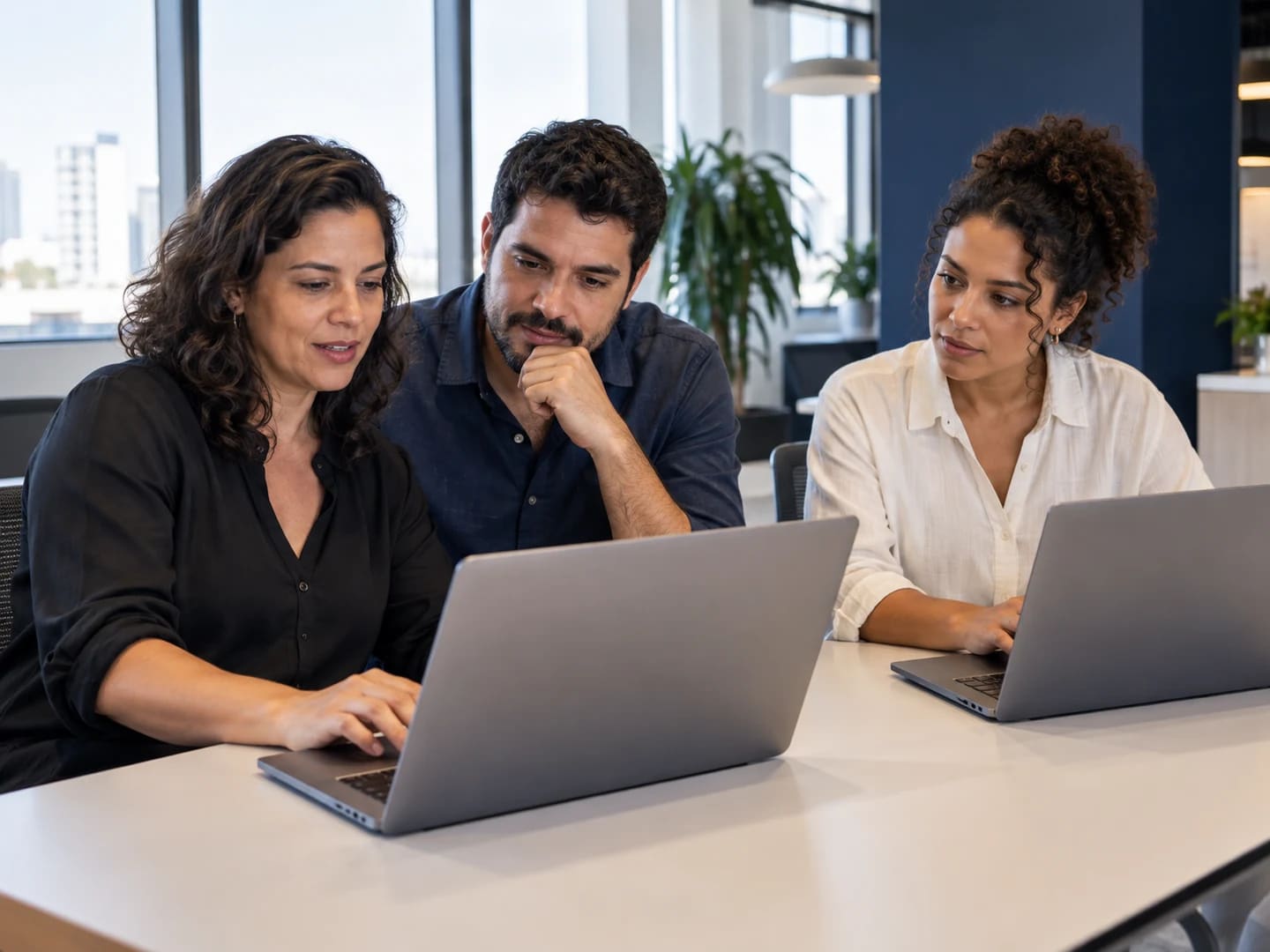 Três profissionais aprendem juntos com notebooks.